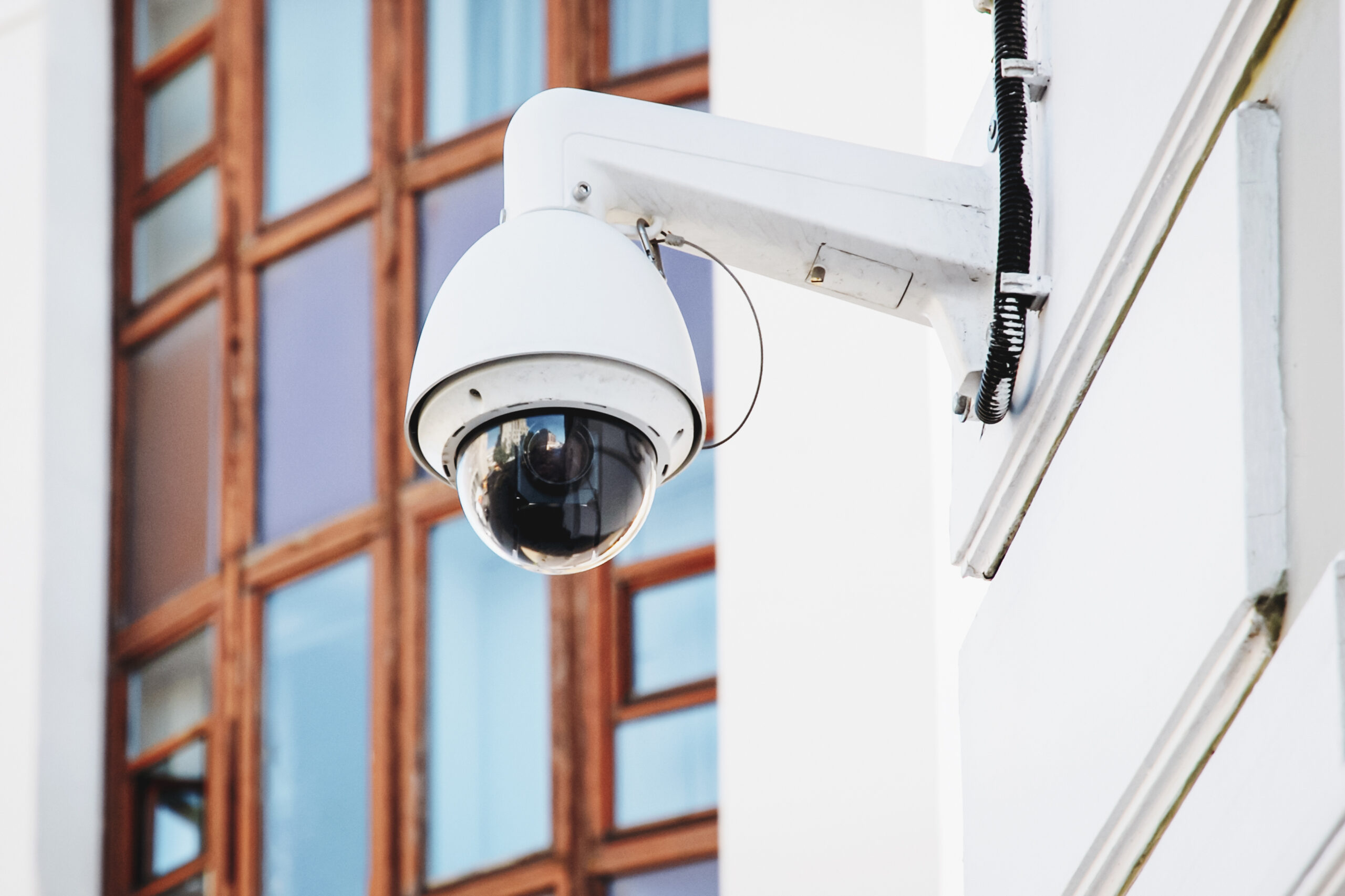 White and black spherical external surveillance camera on building facade
